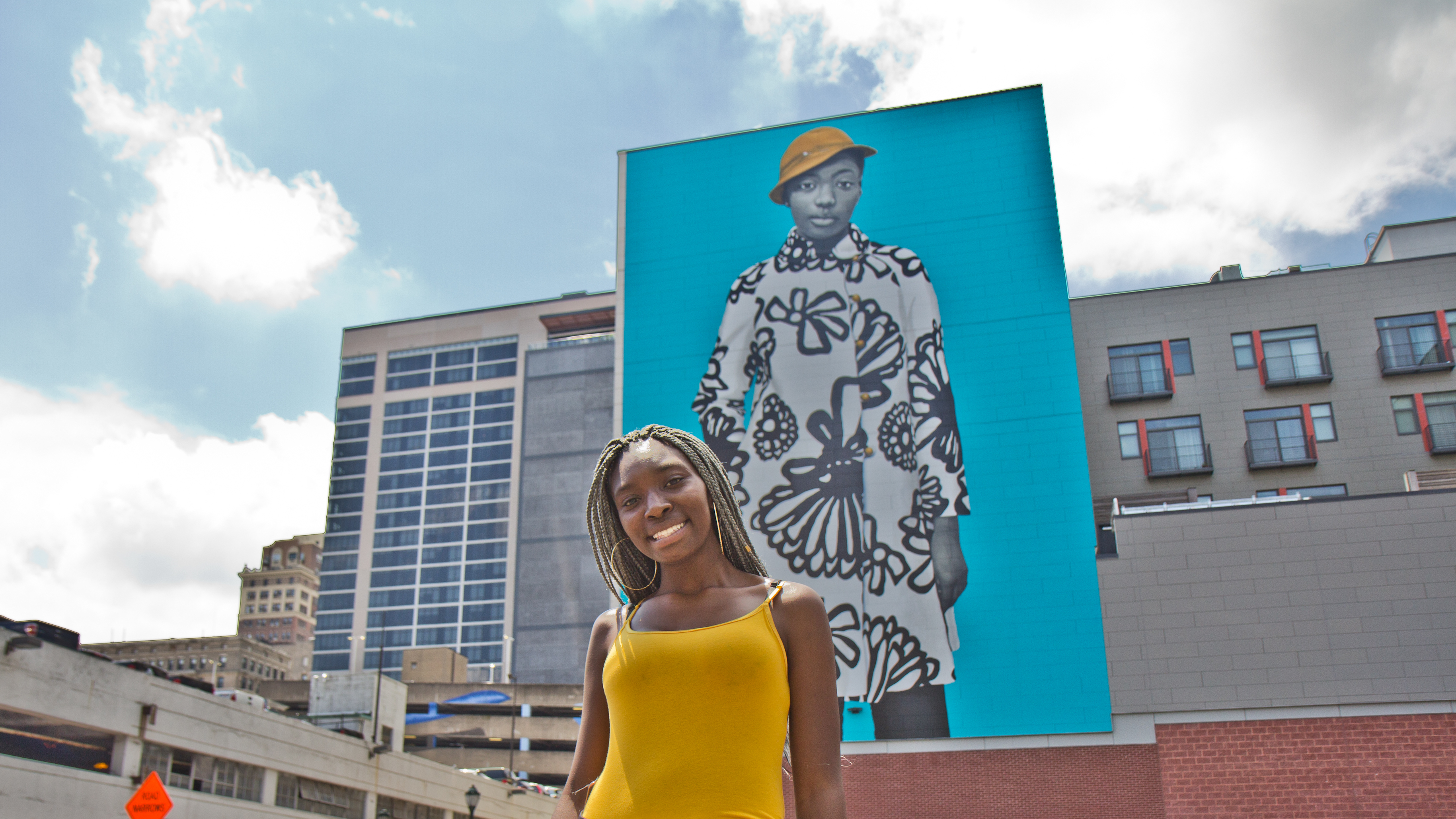 Najee Spencer-Young poses in front of her mural portrait by artist Amy Sherald.