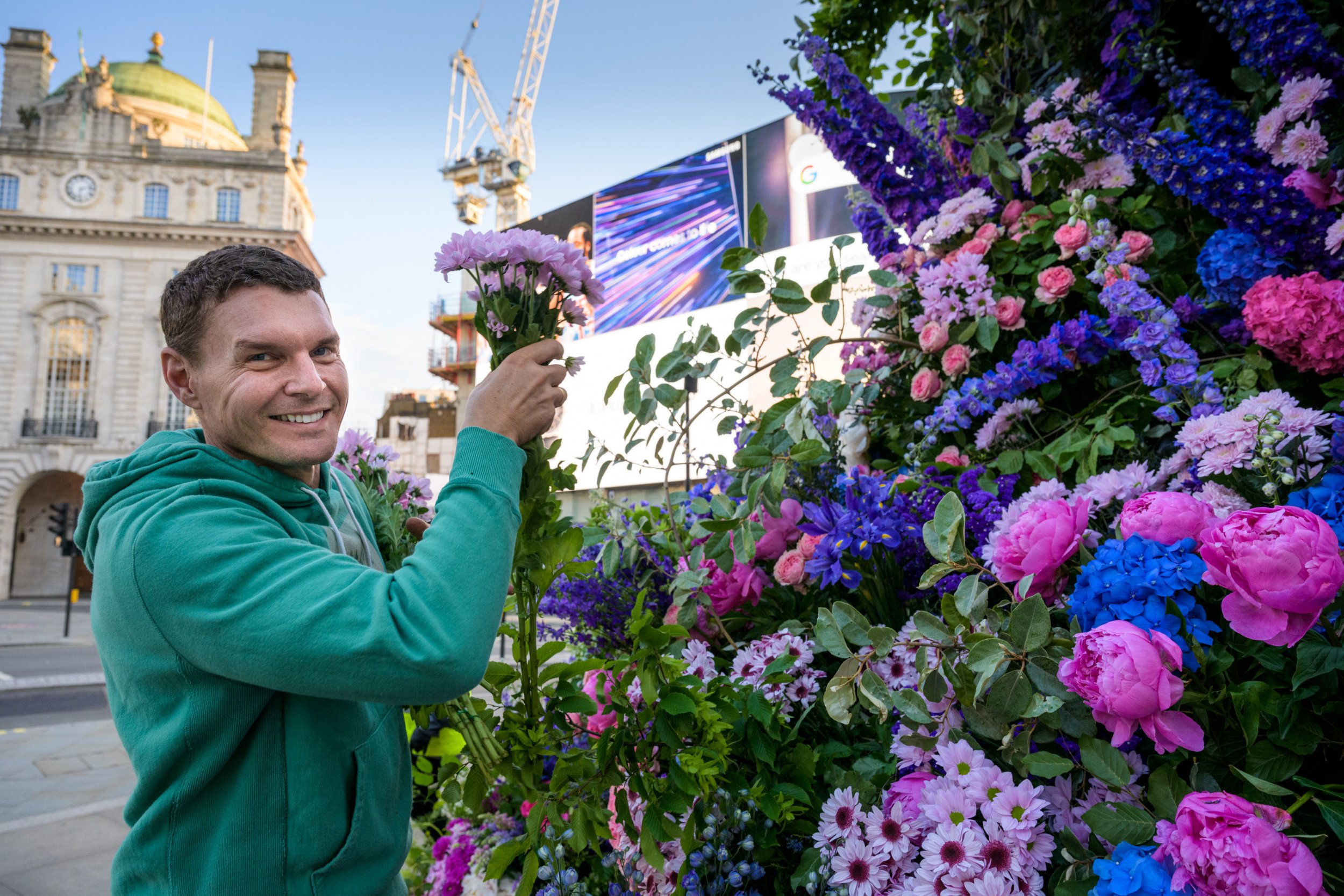 EDITORIAL USE ONLY Lewis Miller puts the finishing touches to a floral display at Eros in Piccadilly as a series of installations dubbed ÔFlower FlashesÕ by he and US floral guru Simon Lycett, which also goes on display in Brick Lane Eros and phone boxes in Great Windmill Street, London. Picture date: Monday June 7, 2021. PA Photo. Lewis Miller is famous in New York for his installations which have featured in taxi cabs, trash cans, building sites and hot dog stalls. More than 20,000 fresh blooms from Covent Garden Flower Market were used to create the artworks. The London flower flashes are part of a campaign called ÔWe Need More FlowersÕ as it is reported online sales of flowers nearly tripled during lockdown. Photo credit should read: Anthony Upton/PA Wire